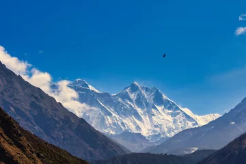 Muurstickers Lhotse A helicopter heads to the Everest base camp and can be seen against the towering Everest and Lhotse walls from Namche Bazaar on a brilliant summer day