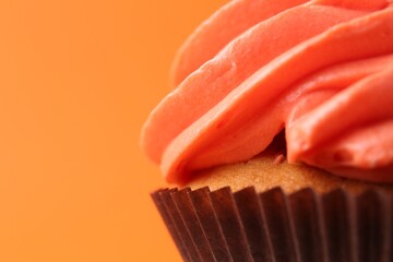 Delicious cupcake with bright cream on orange background, closeup. Space for text