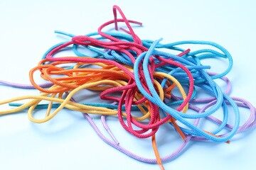 Many colorful shoe laces on light blue background, closeup