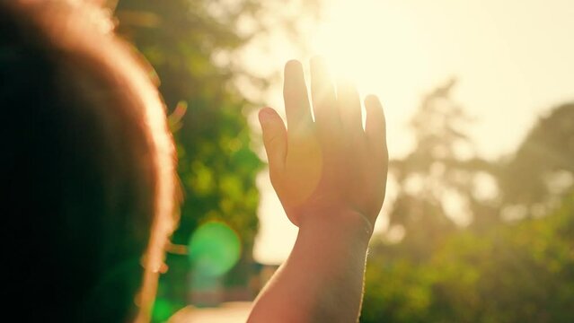 Little girl playing outdoor, Sunlight in hands of child, nature. Happy child boy raises her hands to sun. Kid dreams in park against sun. Child prayer, boy stretches out her hands to sun. Religion.
