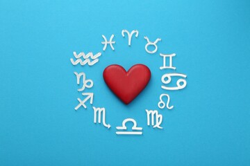 Zodiac signs and heart on light blue background, flat lay