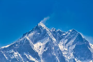 Papier Peint photo Lhotse Jet streams fly off the summit of Mount Lhose, the 4th highest mountain in the world in this telephoto image taken from Namche Bazaar against a blue sky in Khumbu, Nepal