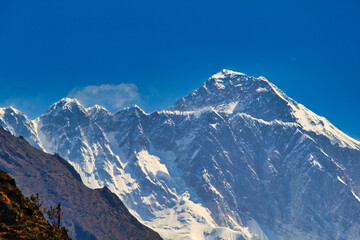 Massive West Face and summit pyramid of Mount Everest in this telephoto image taken from Namche Bazaar against a blue sky in Khumbu, Nepal - obrazy, fototapety, plakaty