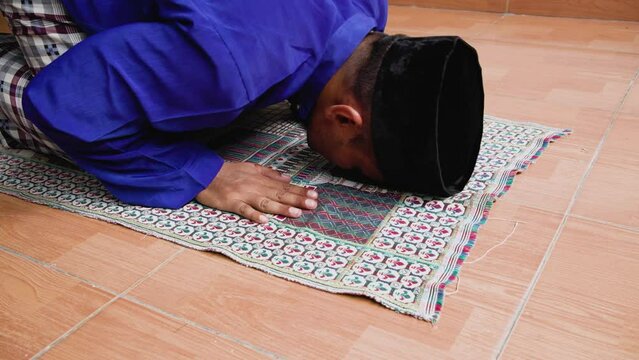 Muslim Indonesian young man praying for Allah at the mosque. Religious muslim Asia man praying inside the mosque.