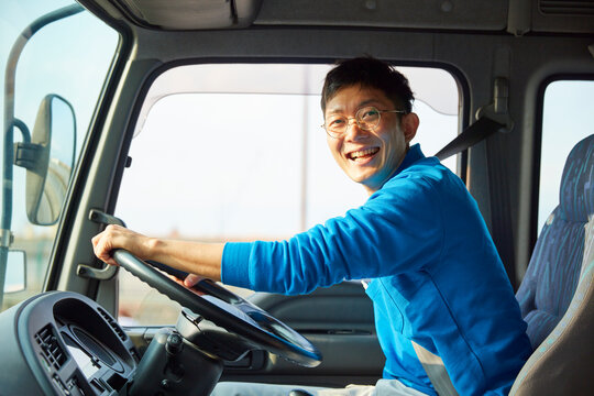 トラックを運転する作業着姿の男性