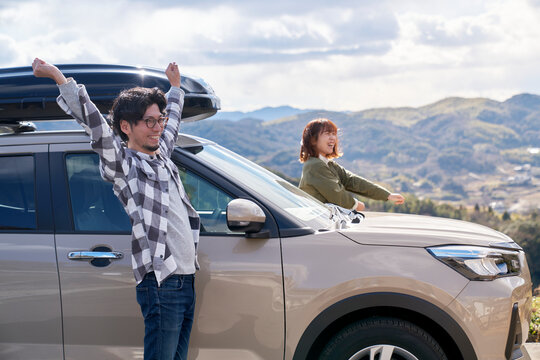 車から降りて伸びをする男女