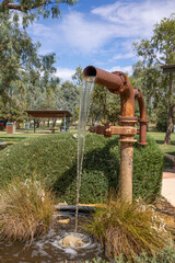 An artesian bore standpipe on display at the visitor information centre splashes water into a pond...