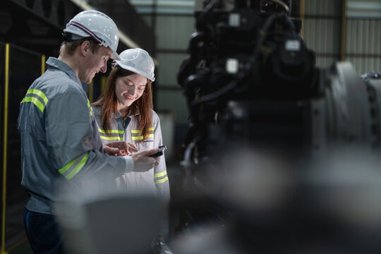 engineers check control heavy machine robot arm. Diverse Team of Industrial Robotics Engineers Gathered Around Machine. Professional Machinery Operators repair electric robot on bright digital panel.
