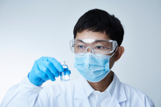 小瓶を眺める白衣を着た研究者