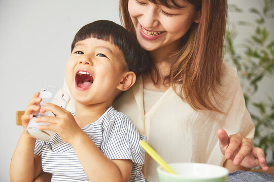 母の膝の上でジュースを飲む男の子