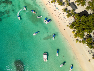 Aerial drone 90 degree straight down shot of white sand beach with many people and moored yachts and boats at the crystal clear turquoise ocean water. South destination, march break, travel concept.
