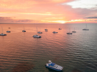 Aerial drone photo of many white yachts and boats at the calm turquoise ocean water shot at sunset...