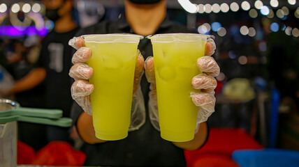  Two glasses of sugar cane ice in hand held on a bokeh background