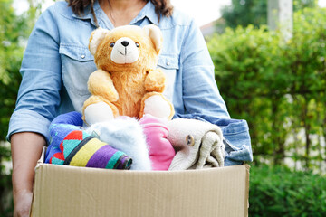 Volunteer collect cloth and doll in cardboard box to donate.