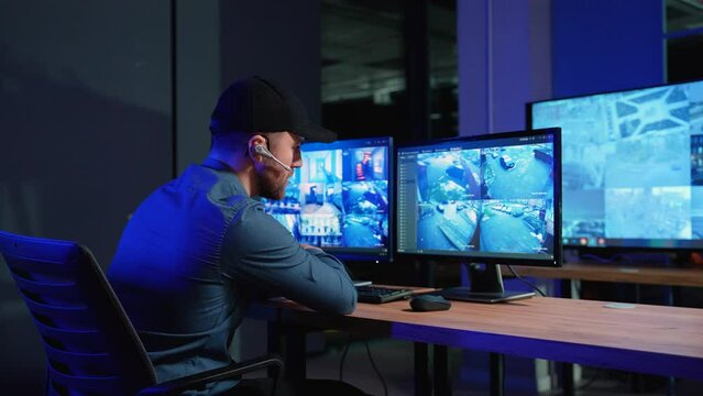 Security officer with headset watching the screens talking on radio in control room