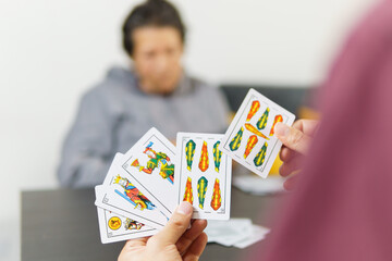 a man playing spanish cards or tute with his mom