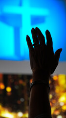Silhouette Hand Raising Worshipper, blurred christian cross background