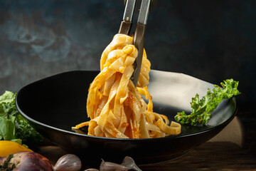 photograph of fettuccini carbonara noodles with tomato sauce garlic various seasonings in an old frying pan giving flavor to the food