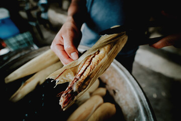 Elote callejero, maíz tierno cocinado con especias, ensartado en un palo de madera cubierto con...