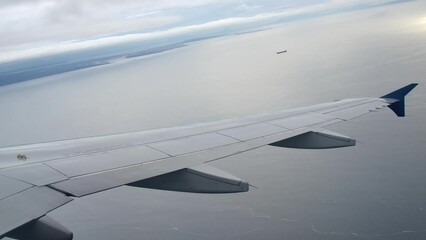 Passenger View of Airplane Wing Flying Above the Sea, Cloudy Day