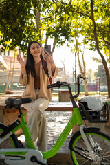 Beautiful woman taking a bike stroll in the park, business woman holding smartphone using bike rental,  business woman holding smartphone using bike rental digital phone