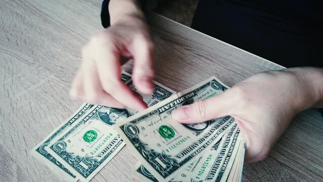Close-up of a woman's hands counting a cache of American dollars.