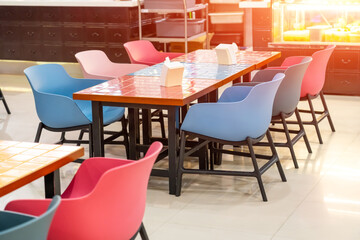 Plastic chairs and wooden tables with colored bright ceramic tiles in squares.