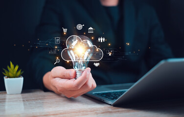 Innovative Technology Concept with Light Bulb Graphic Person holding a light bulb with glowing cloud computing and business icons symbolizing innovation and technology solutions