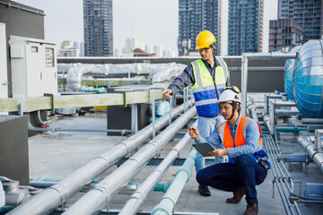 Asian man engineer holding tablet working at rooftop building construction. Male technician worker...
