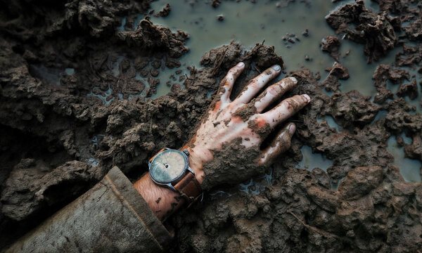 Stuck in the mud. A dead soldiers hand and broken watch lays in mud on a World War 1 (WW1) battlefield. Memento Mori.