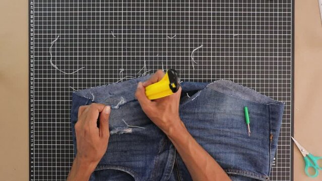 Person cutting with cutter and reshaping shorts. Close up