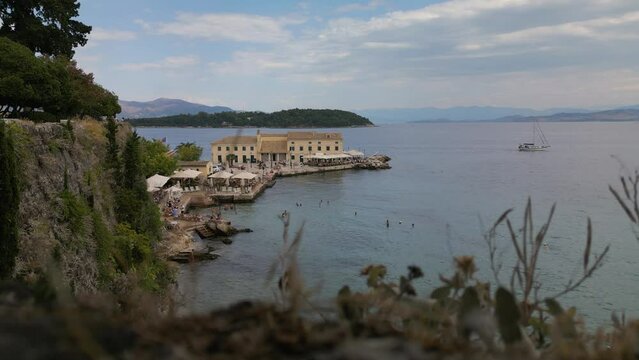 Static establishing shot of old Greek hotel at edge of rocky coastline in Corfu Greece