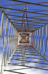 pylon with high voltage cables for the transport of electricity and white clouds on the sky