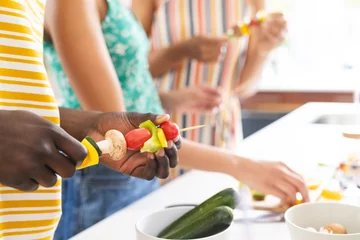  Diverse group of people preparing vegetable skewers in a bright kitchen © WavebreakMediaMicro