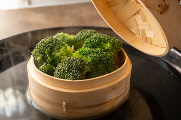 boil steaming broccoli with bamboo steamer on black surface
