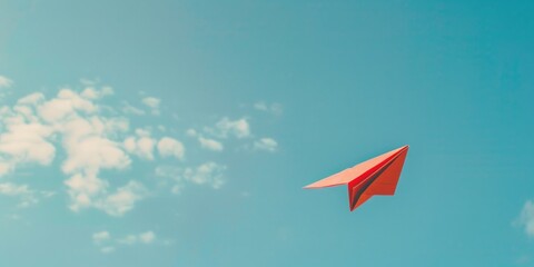 Red paper airplane flying in sky