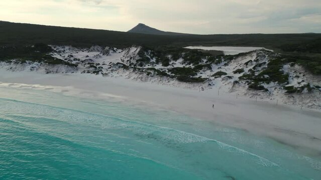 aerial view over Thistle Cove in Cape Legrand wth someone walking on the bach and the frenchman peak in the background, cape legrand national park near esperance, western australia