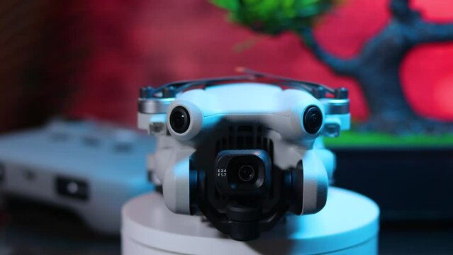 Quadcopter frontal view, folded with the controller in the background, with blue lighting fading away, DJI Mini 4 Pro drone epic shot