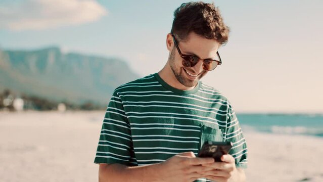 Man, phone and laughing for fun on beach, smile and internet for comic meme on social media. Happy male person, wind and online for funny blog or website, comedy and humor on summer holiday at sea