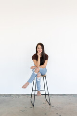 Smiling woman on stool in jeans and top