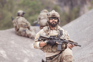 Fototapeta premium Soldiers in camouflage military uniforms carrying weapons, Reconnaissance missions in rugged mountains, Assault infantry battle training.