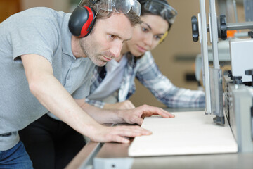 two carpenters making holes in wood plank