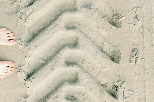 Feet and Tire Tracks in Sand