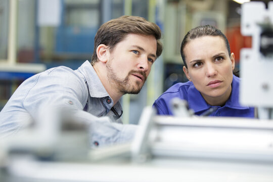 portrait of man and woman behind industrial machine