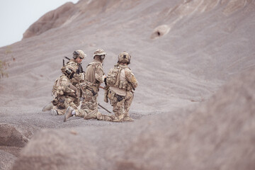 Soldiers in camouflage military uniforms carrying weapons, Reconnaissance missions in rugged...