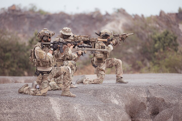 Fototapeta premium Soldiers in camouflage military uniforms carrying weapons, Reconnaissance missions in rugged mountains, Assault infantry battle training.