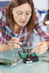 woman soldering a circuit board in her tech office