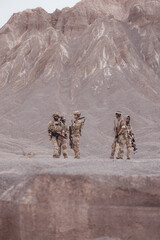 Soldiers in camouflage military uniforms carrying weapons, Reconnaissance missions in rugged...