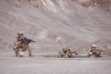 Soldiers in camouflage military uniforms carrying weapons, Reconnaissance missions in rugged...