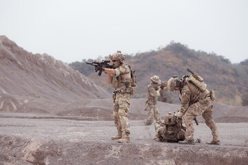 Soldiers in camouflage military uniforms carrying weapons, Reconnaissance missions in rugged...